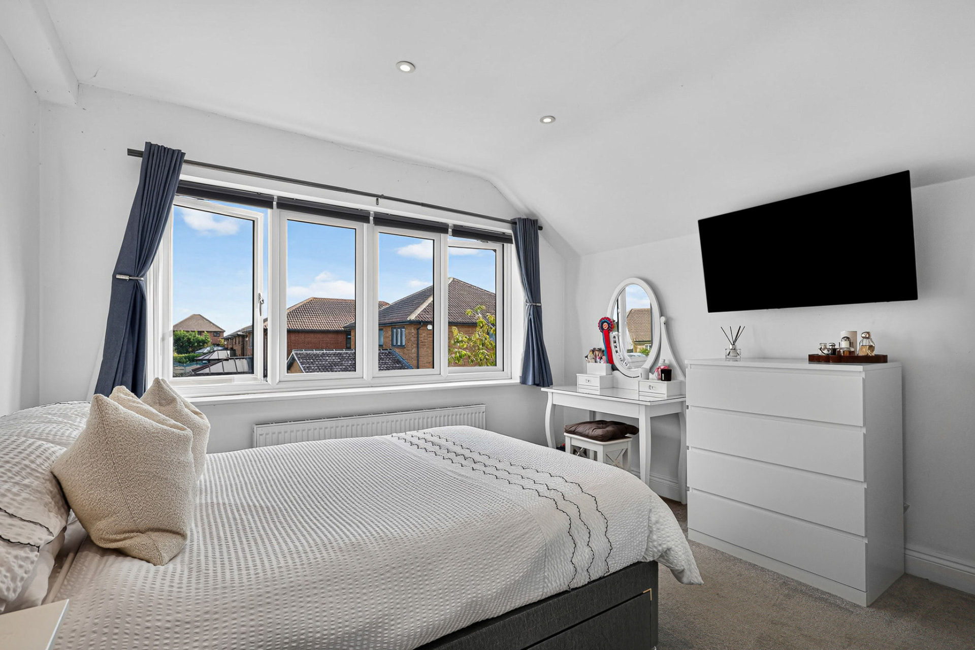 Bright principal bedroom with a wide window and neutral furnishings