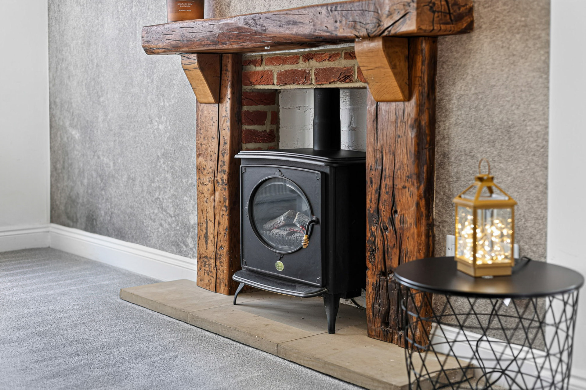 Rustic timber fireplace with a black wood-burning stove and illuminated lantern